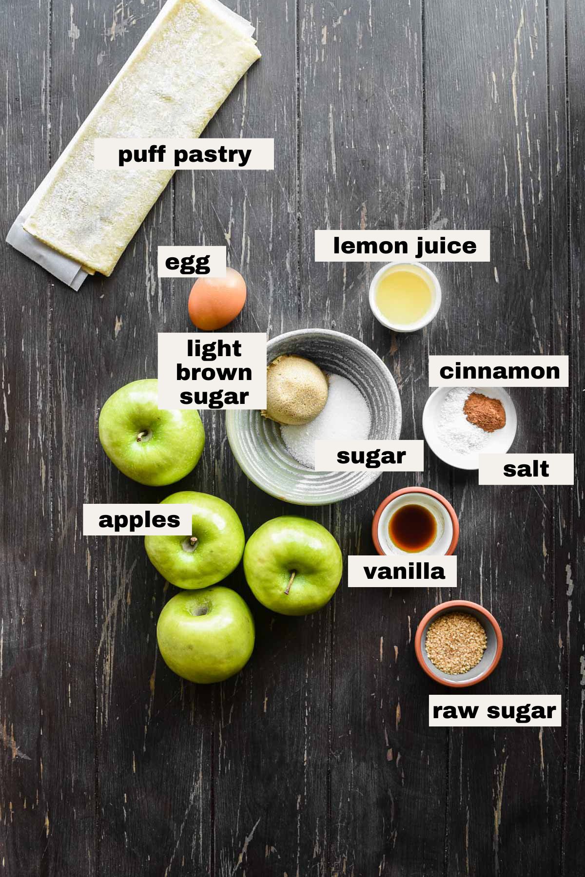 Ingredients to make puff pastry apple galette on a table and labeled.
