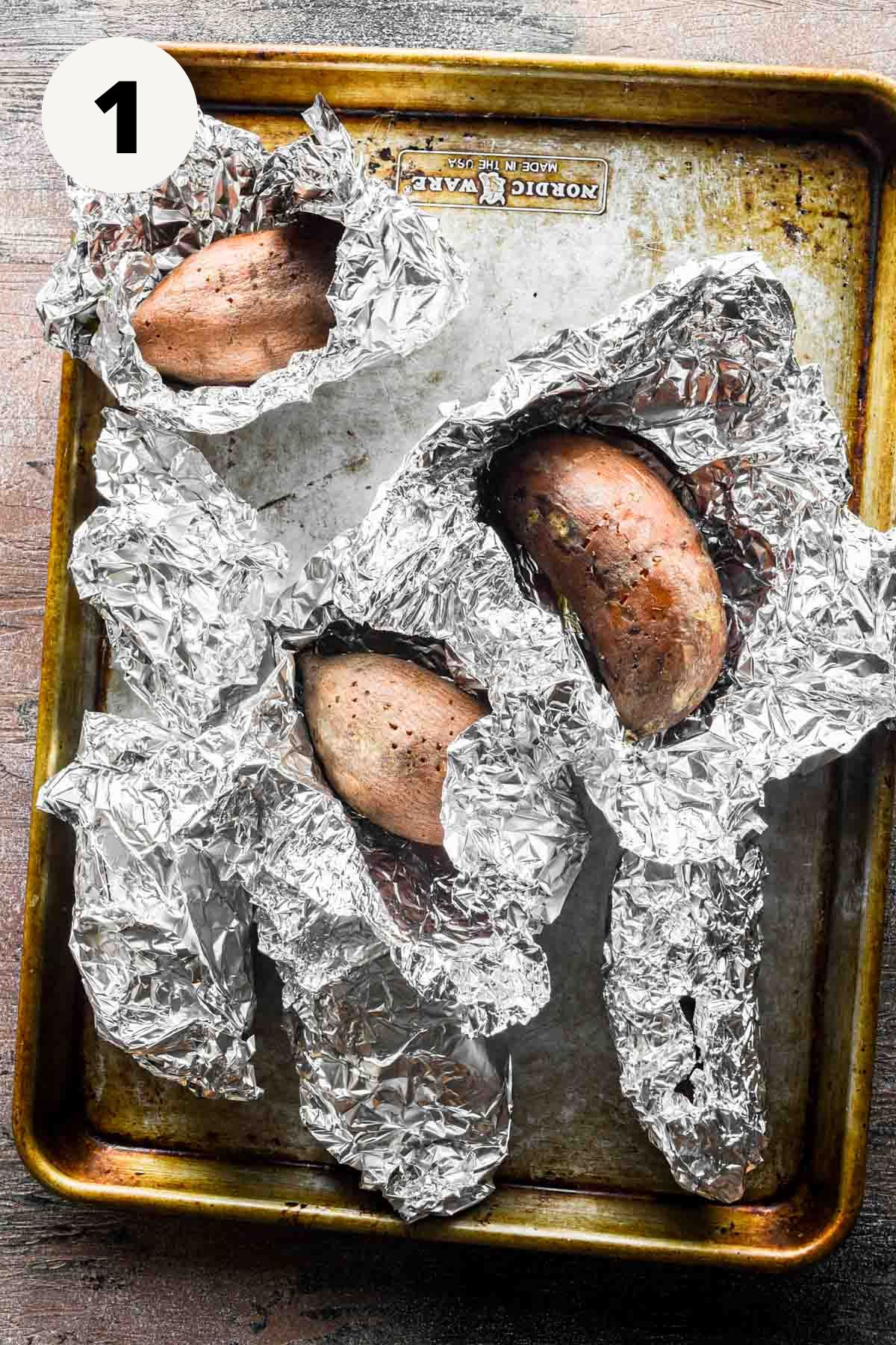 Wrapped sweet potatoes on a sheet tray.
