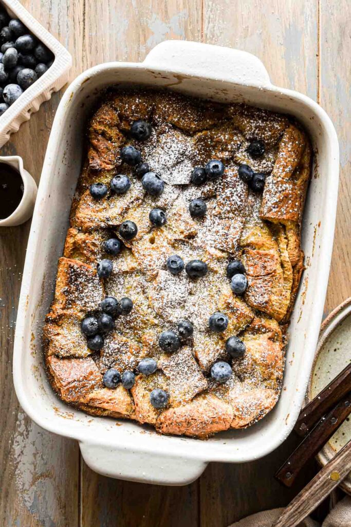Overhead image of french toast in a casserole dish with powdered sugar and blueberries.