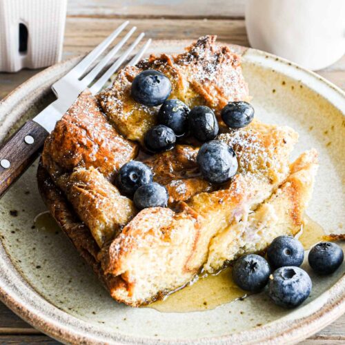 straight-on image of a slice of brioche french toast casserole with blueberries.