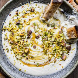 Feta dip in a bowl with honey and pistachios on top.