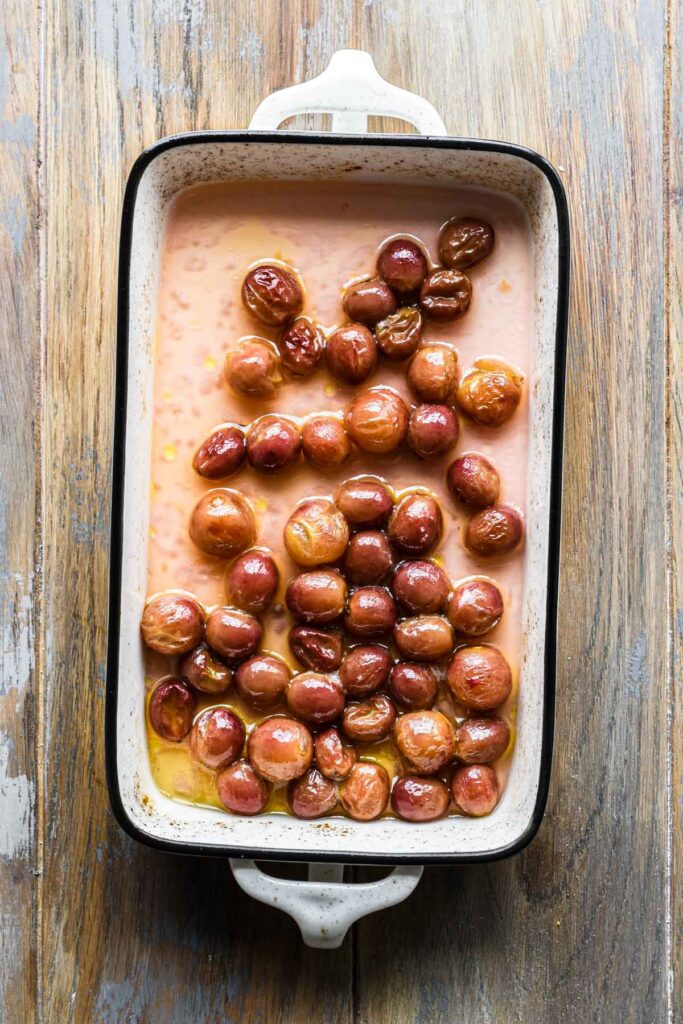 Roasted grapes in a small baking dish.