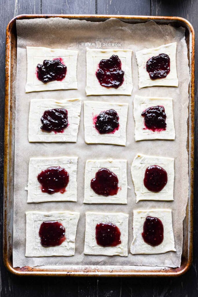 Adding jam to the center of puff pastry.