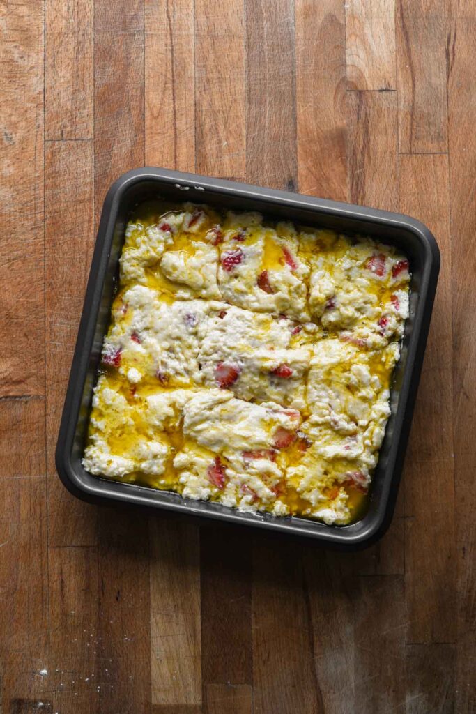 Biscuit dough cut into squares in the pan.