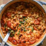 Tomato beans in a cast iron dish with cheese and bread.